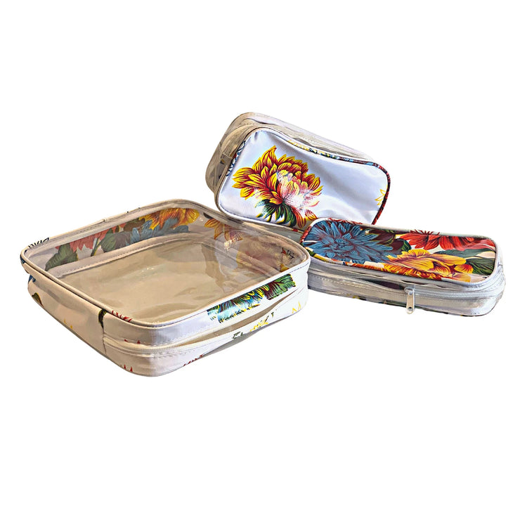 Above view: One large case and two small travel cases, multi-colored flower print on white background.