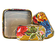 Front view: One large case and two small travel cases, multi-colored flower print on mustard background.