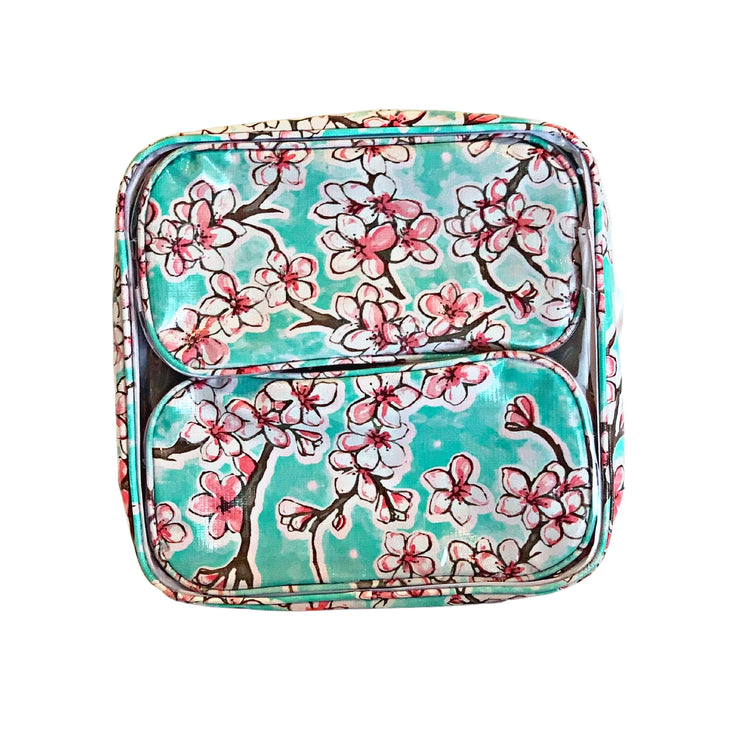 Front view: Two small travel cases, multi-colored cherry blossom print on green background, fitting inside the large case.