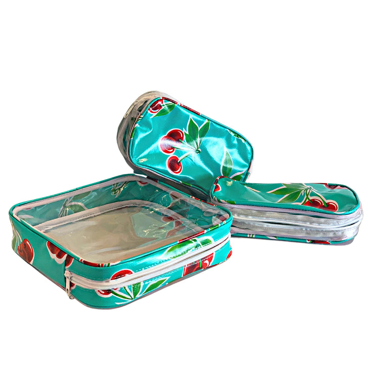 Above view: One large and two small travel cases, cherry print on green background.