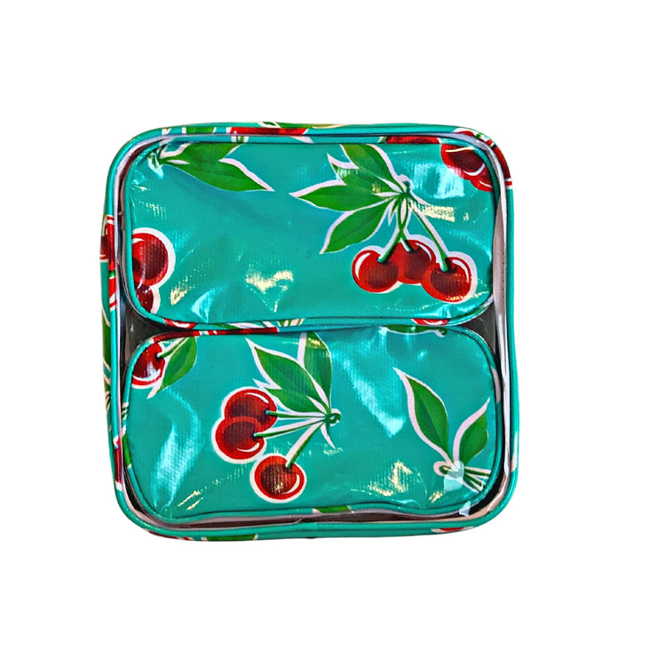 Front view: Two small travel cases, cherry print on green background, fitting inside large case.