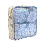 Side view:  Two small travel cases, white floral print on silver background, fitting inside the large case.