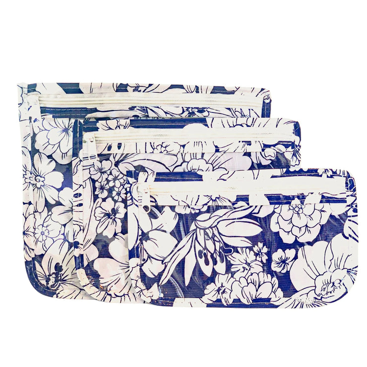 Front view: Small, medium and large slim travel bags, white zippers and white floral print on a blue background.