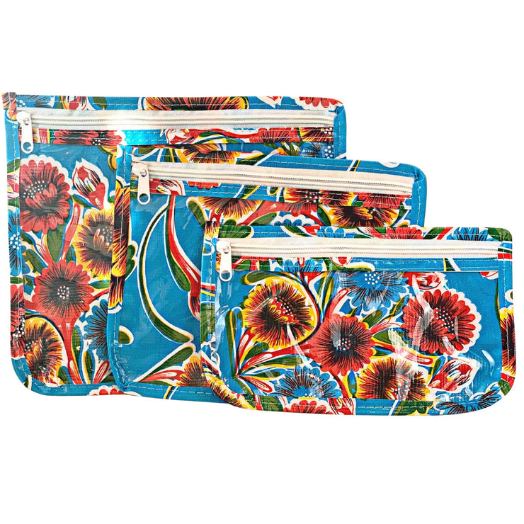 Front view: Small, medium and large slim travel bags, white zippers and multi-colored floral print on blue background.