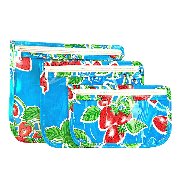 Side view: Small, medium and large slim travel bags, white zippers and strawberry print on blue background.