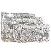 Front view: Small, medium and large slim travel bags, white zippers and white floral print on a gray background. 
