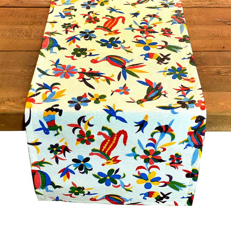 Above view: Multi-colored animal/floral print table runner on wooden table. 