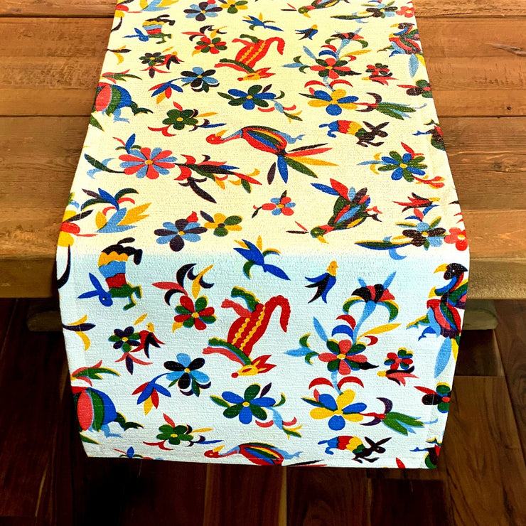 Above view: Multi-colored animal/floral print table runner on wooden table.