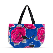 Front view: Large pink rose print on blue background tote with black handles. 