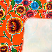 Close up: Multi-colored floral print on terracotta background with white underside folded up to show contrast. 