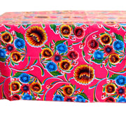 Side view: Multi-colored floral print on pink background tablecloth covering table.