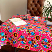 Above view: Multi-colored floral print on pink background tablecloth covering table, with opened notebook displayed. 