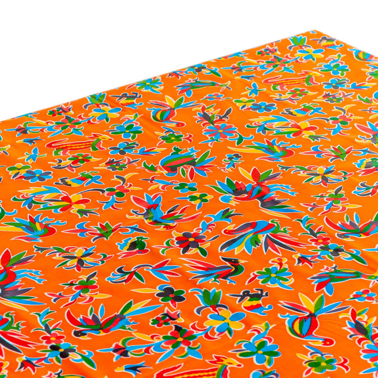 Above view: Multi-colored animal/floral print on orange background tablecloth covering table.