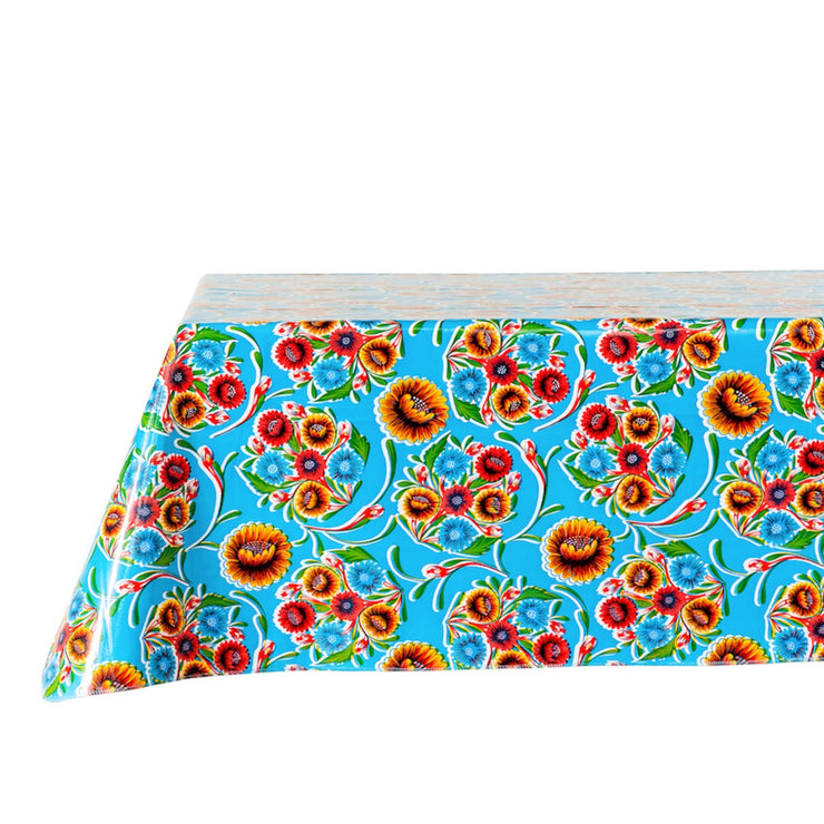 Side view: Multi-colored floral print on light blue background tablecloth covering table.