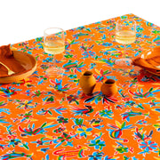 Above view: Multi-colored animal/floral print on orange background tablecloth covering table, with place settings and miniature ceramic centerpieces.