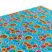 Above view:  Multi-colored floral print on light blue background tablecloth covering table.