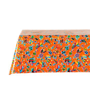 Side view: Multi-colored animal/floral print on orange background tablecloth covering table.