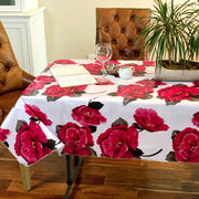 Above view: Roses print  on white background tablecloth covering table, with potted plant centerpiece.