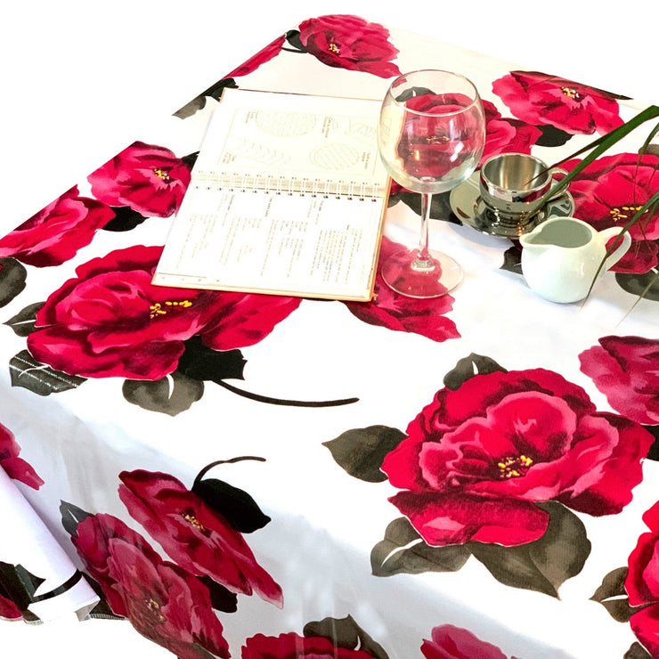 Above view: Roses print on white background tablecloth covering table, with open book displayed.