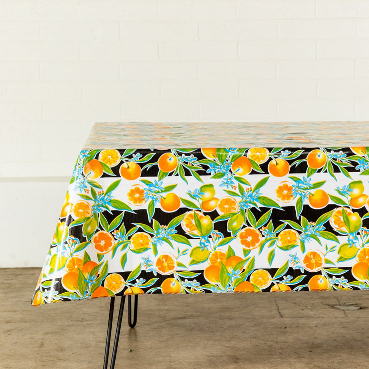 Side view: Orange fruit print on black and white background tablecloth covering table.