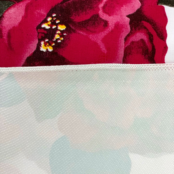 Close up: Roses print on white background tablecloth with white underside folded up to show contrast.