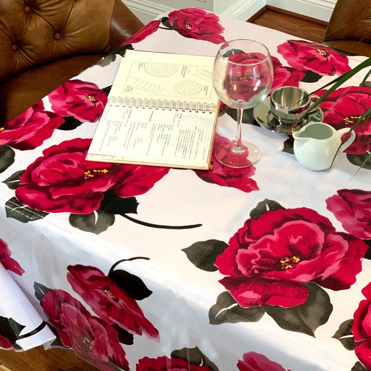 Above view: Roses print on white background tablecloth covering table, with open notebook displayed. 