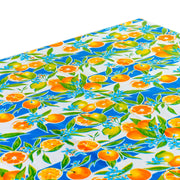 Above view: Orange fruit print on blue and white background tablecloth covering table.