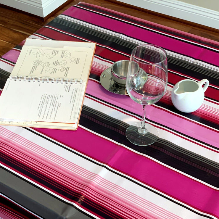 Above view: Multi-colored vertical striped patterned tablecloth covering table, with open book displayed. 