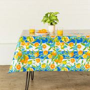 Side view: Orange fruit print on blue and white background tablecloth covering table, with potted plant centerpiece.