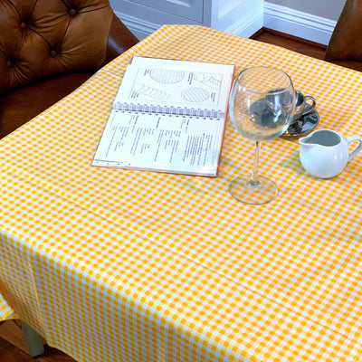 Above view: Yellow and white checkered pattern tablecloth covering table with open notebook displayed.