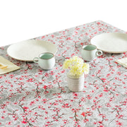 Above view: Cherry blossom print on gray background tablecloth covering table, with place settings and potted flower centerpiece.