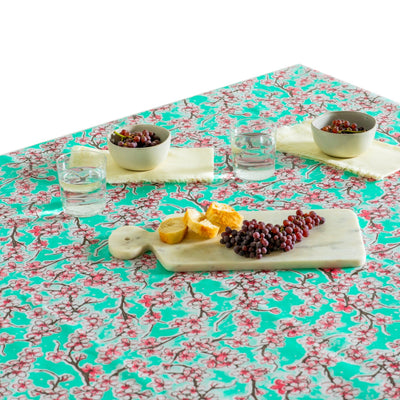 Above view: Cherry blossom print on mint green background tablecloth covering table with platters of grapes.