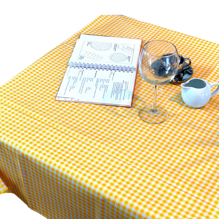 Above view: Yellow and white checkered pattern tablecloth covering table, open notebook displayed.