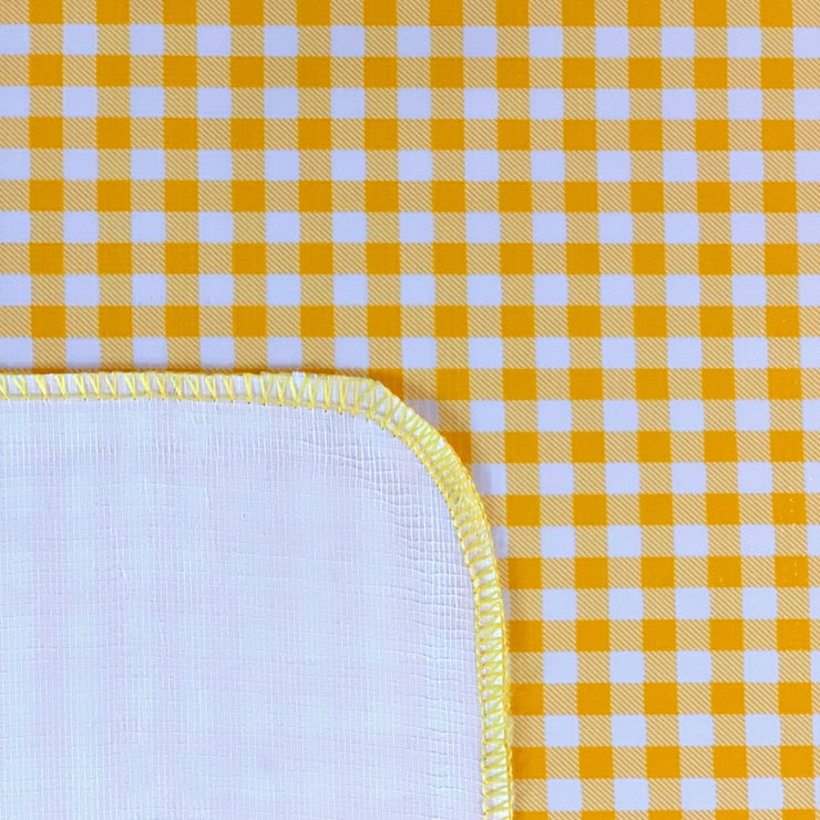 Close up: Yellow and white checkered pattern tablecloth, white underside folded up to show contrast.