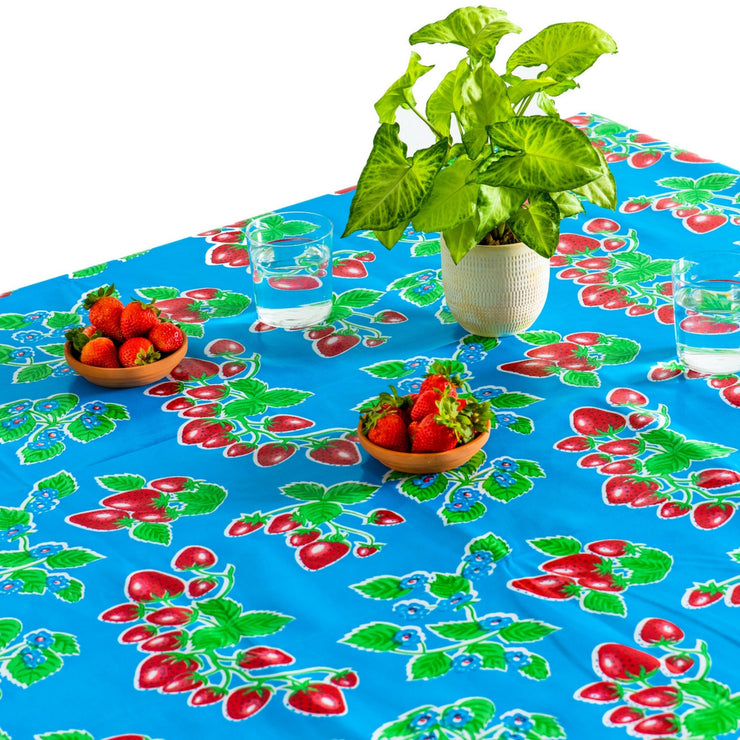 Above view: Strawberry print on blue background tablecloth covering table with potted plant centerpiece.