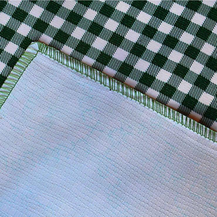 Close up: Green and white checkered pattern tablecloth, white underside folded up to show contrast.