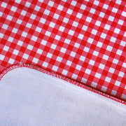 Close up: Red and white checkered pattern tablecloth, white underside folded up to show contrast.