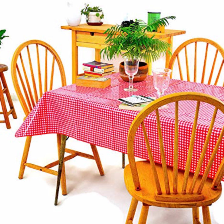 Side view: Red and white checkered pattern tablecloth covering table, potted plant centerpiece and stack of books. 