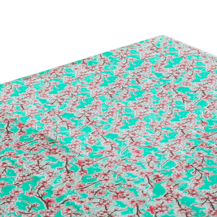 Above view: Cherry blossom print on mint green background tablecloth covering table.