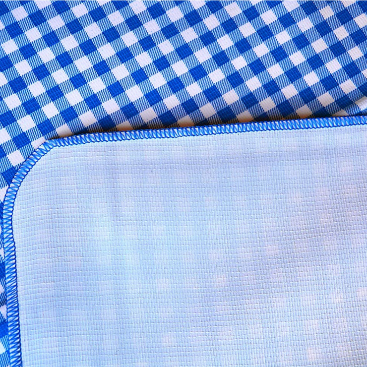 Close up:  Blue and white checkered pattern tablecloth, white underside folded up to show contrast. 