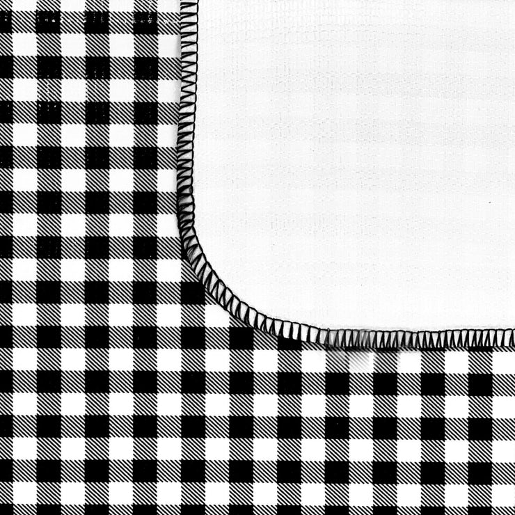 Close up:  Black and white checkered pattern tablecloth, white underside folded up to show contrast.