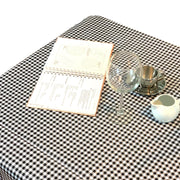 Above view: Black and white checkered pattern tablecloth, open notebook displayed. 