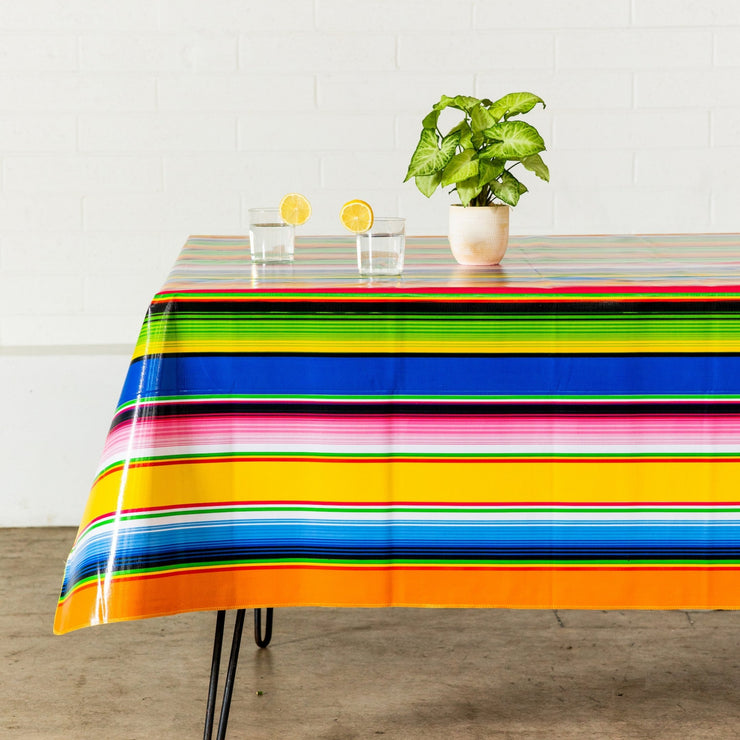 Side view: Multi-colored vertical striped patterned tablecloth covering table, with potted plant centerpiece.