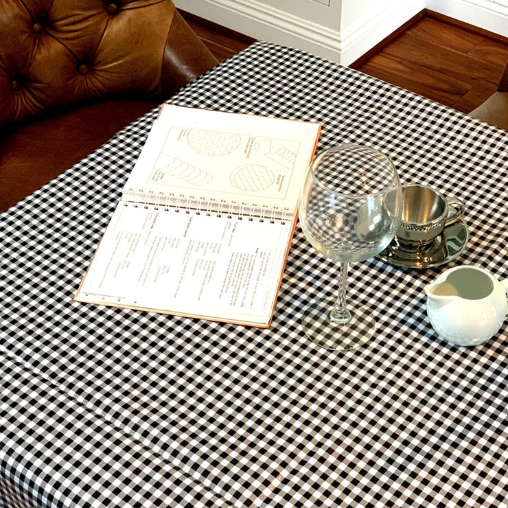 Above view: Black and white checkered pattern tablecloth, open notebook displayed. 