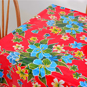 Above view: Multi-colored hibiscus print on red background tablecloth covering table.