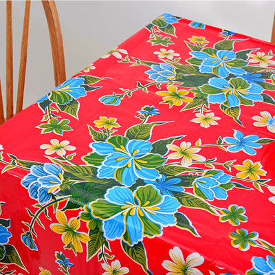 Above view: Multi-colored hibiscus print on red background tablecloth covering table.