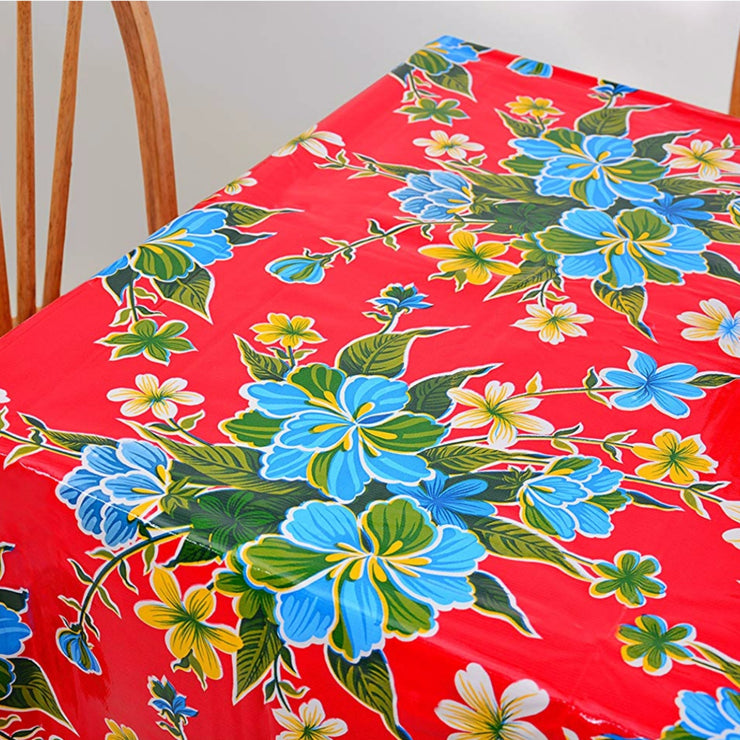 Above view: Multi-colored hibiscus print on red background tablecloth covering table.