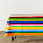 Side view: Multi-colored vertical striped patterned tablecloth covering table.