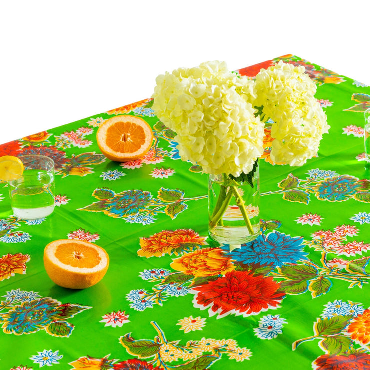 Above view: Multi-colored floral print on green background tablecloth, covering table, with flower centerpiece.