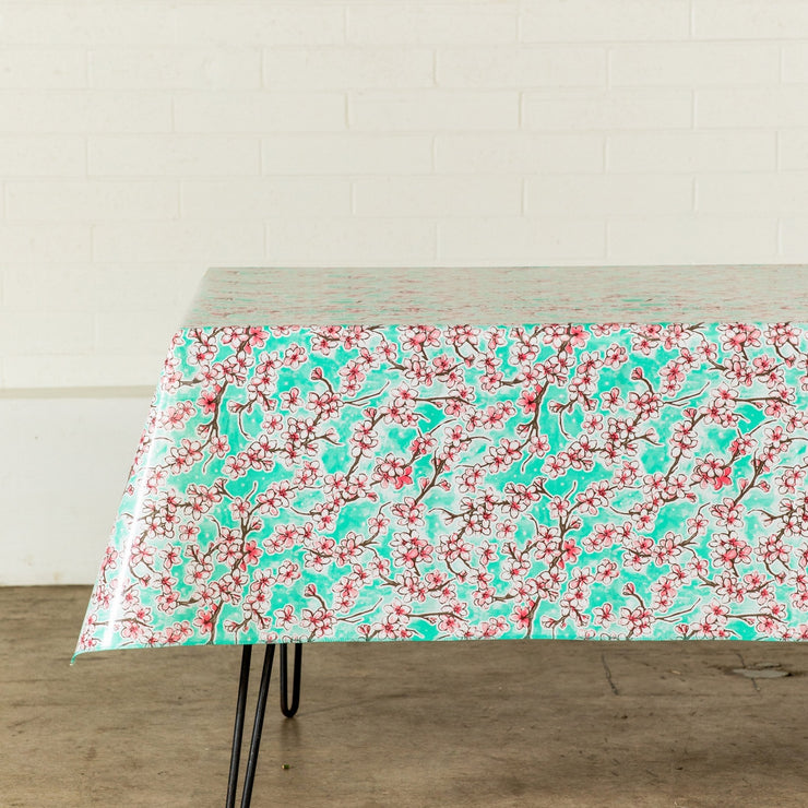 Side view: Cherry blossom print on mint green background tablecloth covering table.